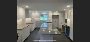 Modern kitchen remodel featuring white cabinetry, granite island, and natural light from window, showcasing home improvement potential for Southern NH homeowners.
