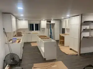 Kitchen remodel in progress featuring white cabinets, an island, and unfinished flooring, illustrating home improvement services by Next Step Property Services in Southern NH.