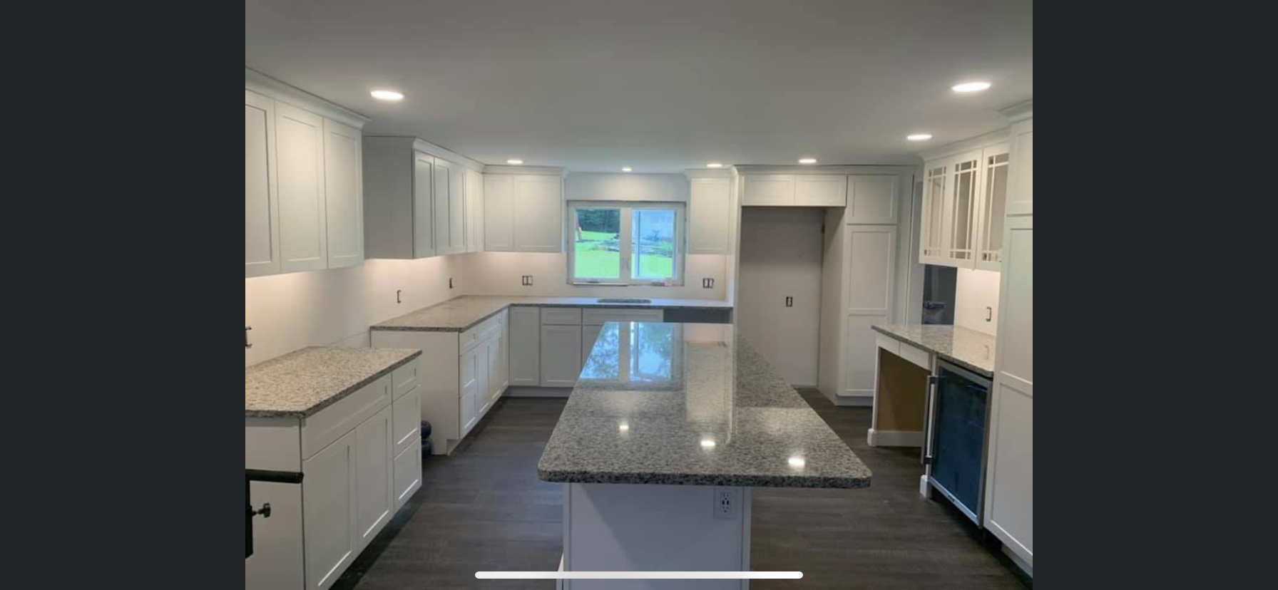 Modern kitchen renovation featuring white cabinets, granite countertops, and a window overlooking greenery, highlighting Next Step Property Services' kitchen remodeling expertise in Manchester, NH.