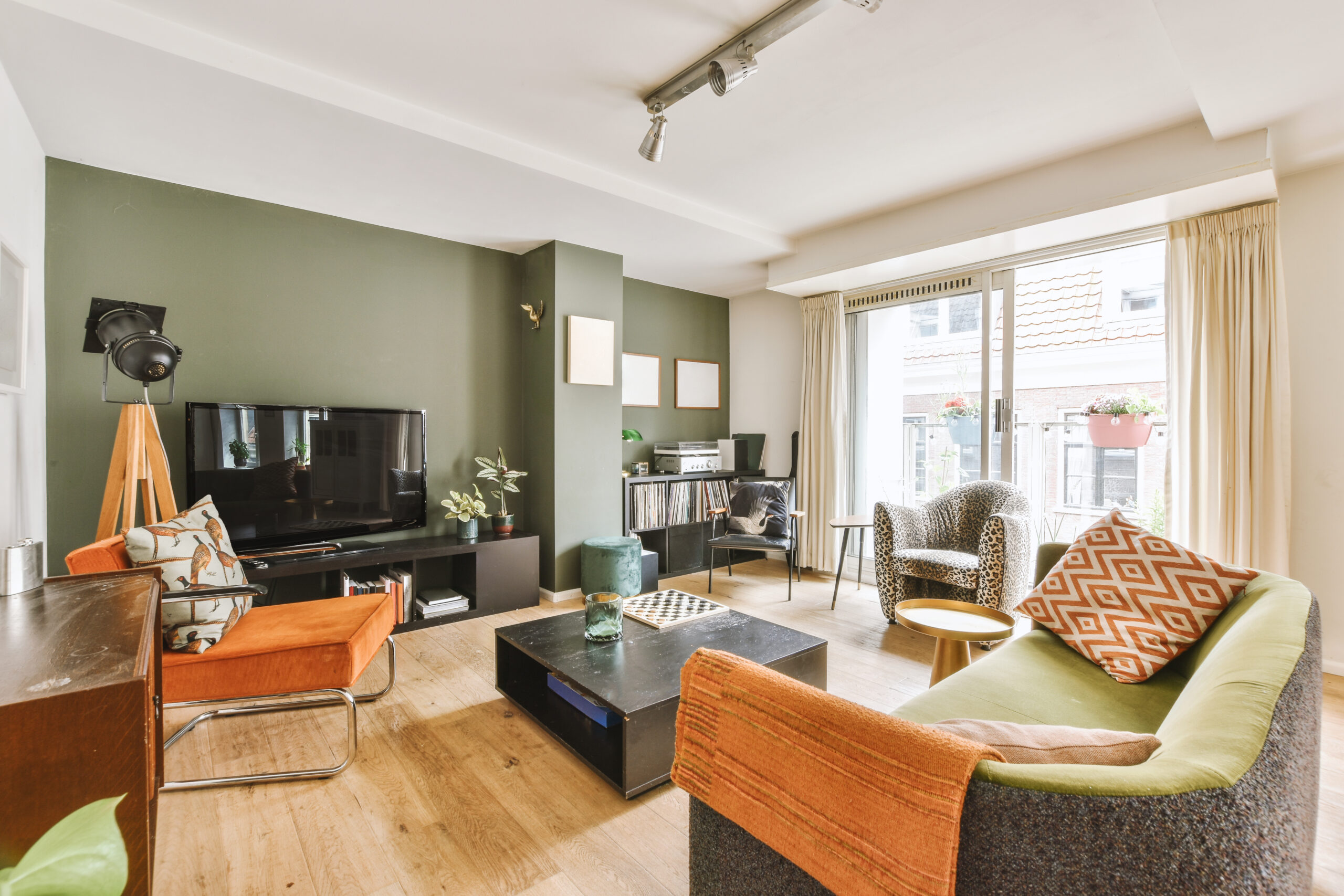 Studio apartment interior featuring modern wooden furniture, green accent wall, and cozy seating area, ideal for rental turnover services in Southern New Hampshire.